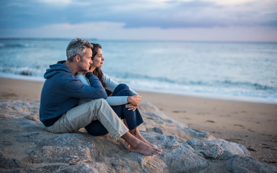 Couple sitting on the beach looking off into the distance