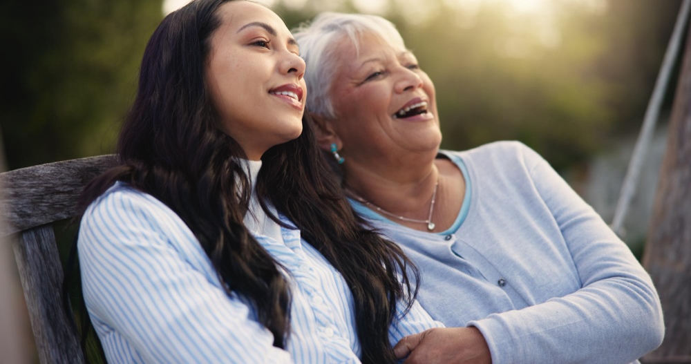 A woman and her mother sitting together on a bench