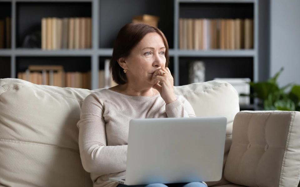 older woman looking pensive with laptop