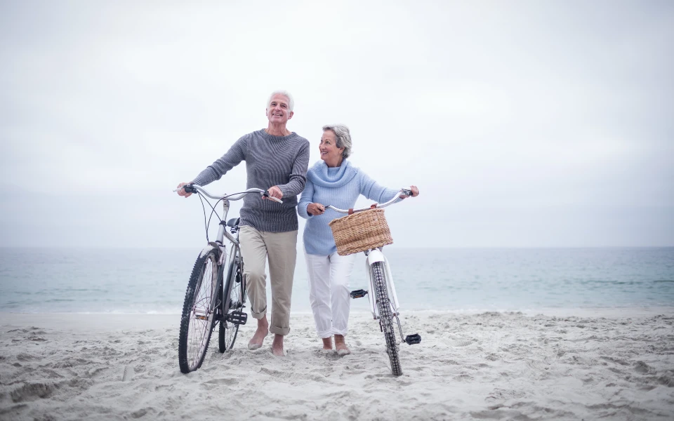 older couple biking at the beach