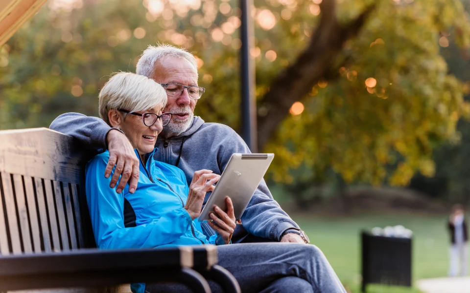 older couple in a park on a tablet